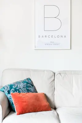 a white couch with a red and blue pillow on it at Charming Apartment With Vibrant Accents in Hospitalet de Llobregat