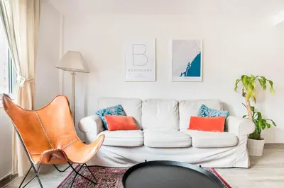 a living room with a white couch and orange pillows at Charming Apartment With Vibrant Accents in Hospitalet de Llobregat