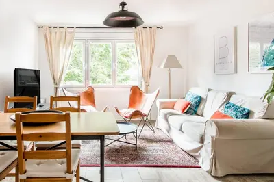 a living room with a white couch and chairs at Charming Apartment With Vibrant Accents in Hospitalet de Llobregat
