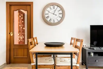 a dining room table with a clock on the wall at Charming Apartment With Vibrant Accents in Hospitalet de Llobregat