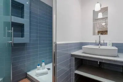 a blue tiled bathroom with a sink and a shower at Historical Apartment With Awesome Rooftop in Barcelona