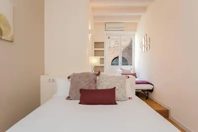 a white bed in a room with a window at Historical Apartment With Awesome Rooftop in Barcelona