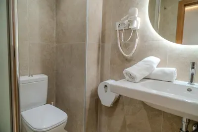 a bathroom with a toilet and a sink and a mirror at HolidaysBCN Rooms in Barcelona