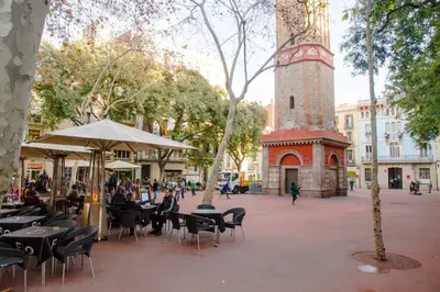 a street with tables and chairs and a clock tower at Studio Gracia By MyRentalHost in Barcelona
