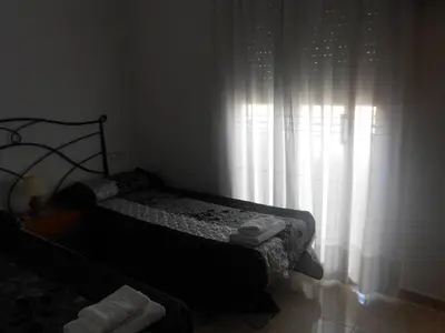 a bedroom with a bed and a window with white curtains at Hostal Ca La Irene in San Vicente de Castellet