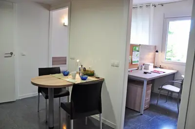 a kitchen with a table and a desk with chairs at Alojamientos Universitarios Resa Hipatia in Terrassa