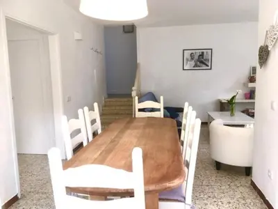 a dining room with a wooden table and white chairs at CASA DEL BOSQUE CON PISCINA EN SITGES in Sant Pere de Ribes