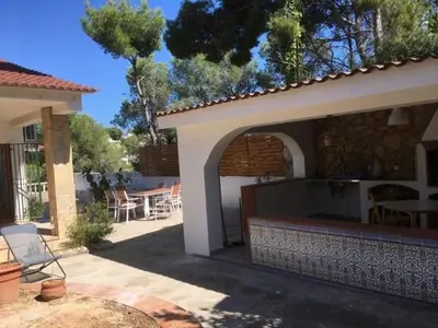 a house with an outdoor patio with a fireplace at CASA DEL BOSQUE CON PISCINA EN SITGES in Sant Pere de Ribes