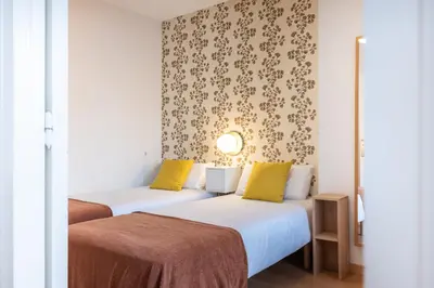 two beds with yellow pillows in a hotel room at Penthouse Apartment with Terrace in Barcelona City Center in Barcelona