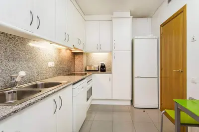 a white kitchen with a sink and a refrigerator at Fabulous Flat By Paseo De Gracia in Barcelona