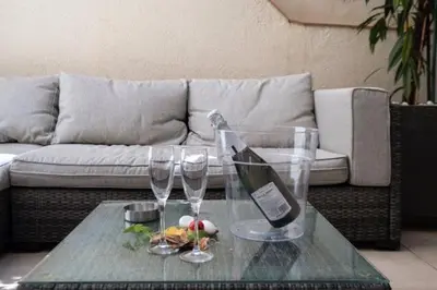 a glass table with a bottle of wine and two glasses at Vive la playa y la noche de Sitges aquí in Sitges