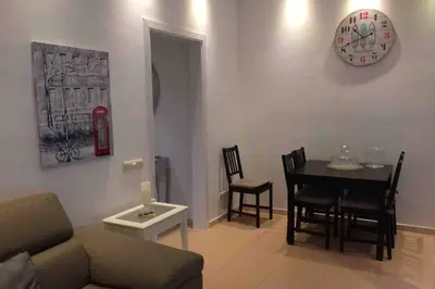 a living room with a table and chairs and a clock at Vive la playa y la noche de Sitges aquí in Sitges