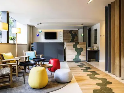 a living room with tables and chairs and a kitchen at ibis Styles Barcelona Centre in Barcelona