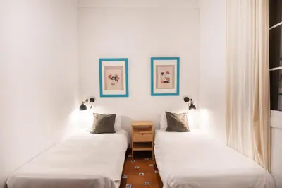 two beds in a room with white walls at Spacious & Sunny Apartment with Terrace in the city center in Barcelona