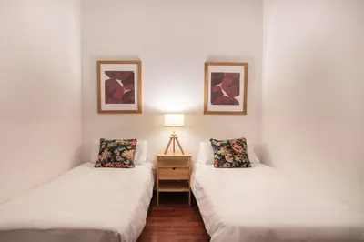 two beds in a room with a lamp and pictures at Spacious & Sunny Apartment with Terrace in the city center in Barcelona