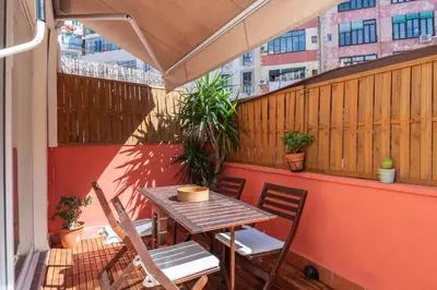 a wooden table and chairs on a balcony with a table at Spacious & Sunny Apartment with Terrace in the city center in Barcelona
