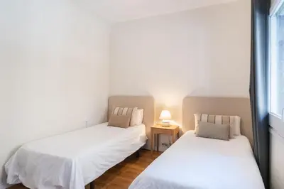 two beds in a room with white walls at Comfortable 3-Bedroom Apartment next to Sagrada Familia, Barcelona in Barcelona