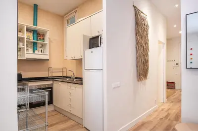a kitchen with white cabinets and a refrigerator at Sunny Central Apartment with 100sqm Terrace in Barcelona in Barcelona