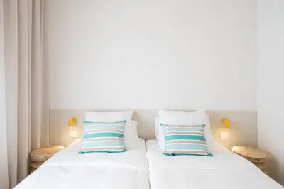 a bed with white sheets and blue and white pillows at Mediterranean Retreat with 4-Bedroom, 3-Bath Apartment in Barcelona in Barcelona
