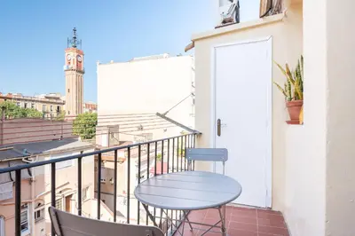 a blue table and chairs on a balcony with a clock tower at Cozy Apartment in the Heart of Gracia, Barcelona in Barcelona
