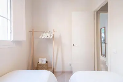 two beds in a white room with a shower at Cozy Apartment with Terrace in Gracia, Barcelona Local Life in Barcelona
