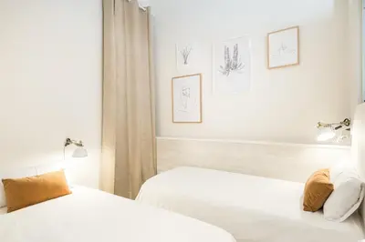 two beds in a white room with drawings on the wall at Sunny Terrace Apartment in Gracia, Barcelona - Local Lifestyle in Barcelona