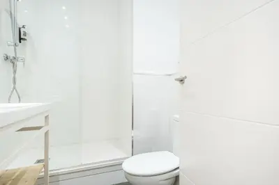 a white bathroom with a toilet and a shower at Sunny Terrace Apartment in Gracia, Barcelona - Local Lifestyle in Barcelona