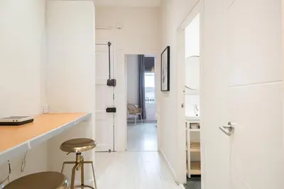 a white kitchen with a counter and a stool at Sunny Terrace Apartment in Gracia, Barcelona - Local Lifestyle in Barcelona