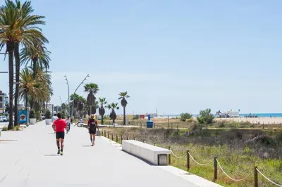 two people walking down a sidewalk near the beach at Maka beach apartment v in Castelldefels