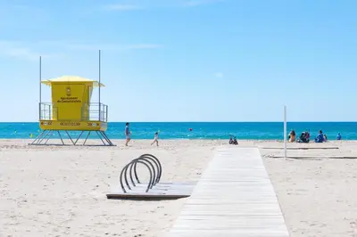 a boardwalk on a beach with a life guard station at Maka beach apartment v in Castelldefels