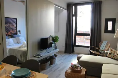 a living room with a bed and a couch and a mirror at Piso nuevo al lado de la Sagrada Familia. in Barcelona