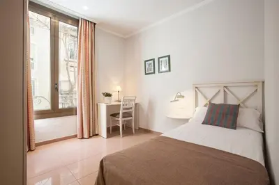 a bedroom with a bed and a desk and a window at BCNGOTIC 11 in Barcelona