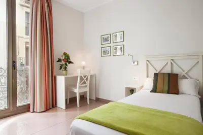 a bedroom with a bed and a desk and a window at BCNGOTIC 31 in Barcelona