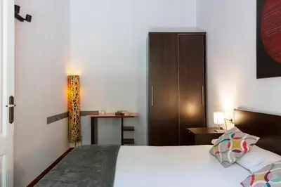 a bedroom with a bed and a cabinet and a table at AB Casanova Apartment in Barcelona