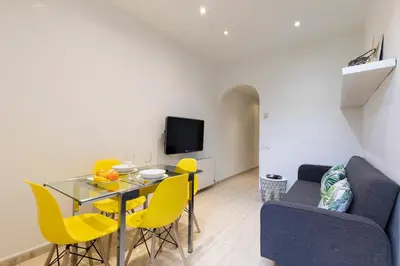 a living room with a dining room table and yellow chairs at AB Rossello Center Terrace in Barcelona