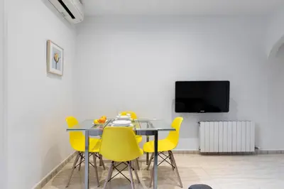 a dining room with a table and yellow chairs at AB Rossello Center Terrace in Barcelona