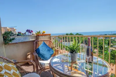 a glass table and chairs on a balcony with the ocean at Palma Fiesta Apartment by Hello Homes Sitges in Sant Pere de Ribes
