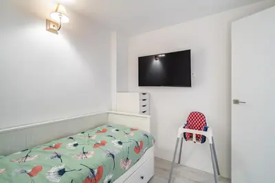 a bedroom with a bed and a chair and a tv at Comtal homey apartments in Barcelona