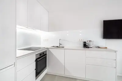 a white kitchen with white cabinets and a tv at Comtal homey apartments in Barcelona