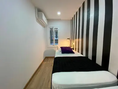 two beds in a room with a striped wall at Besos Beach Gem II By MyRentalHost in Sant Adria de Besos