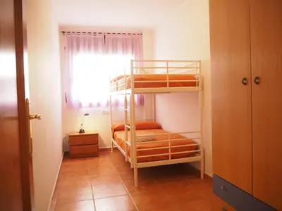 a room with two bunk beds and a window at NINFA Apartamento con balcón ideal familias con vistas al mar in Pineda de Mar