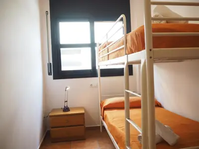 a bedroom with two bunk beds and a window at NINFA Apartamento con balcón ideal familias con vistas al mar in Pineda de Mar