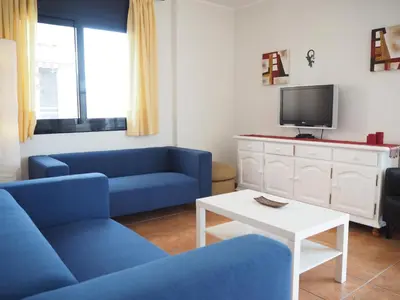 a living room with blue couches and a tv at NINFA Apartamento con balcón ideal familias con vistas al mar in Pineda de Mar