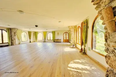 a large room with a wooden floor and a stone wall at Cal Pau Cruset in Torrellas de Foix