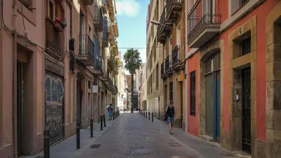 a woman walking down an alley between buildings at Bed&BCN Gracia III in Barcelona