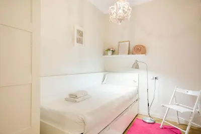 a white bedroom with a white bed and a pink rug at Stay U-nique Apartments Mallorca in Barcelona