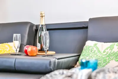 a table with two wine glasses and an apple on a couch at Ghat Apartments Montroig in Sitges