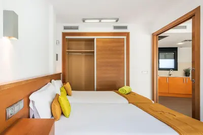 a bedroom with a white bed with yellow pillows at Aparthotel Las Palmeras Castelldefels in Castelldefels