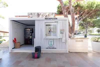 a small white building with a sign on it at Aparthotel Las Palmeras Castelldefels in Castelldefels