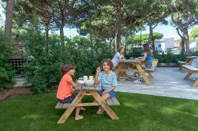 a group of children sitting at a picnic table at Aparthotel Las Palmeras Castelldefels in Castelldefels